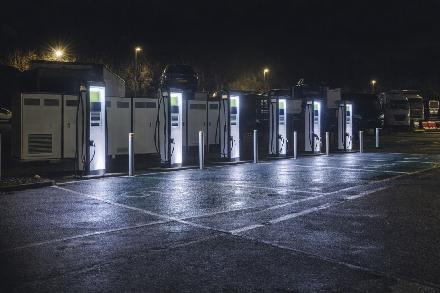 Rivi sähköauton pikalatausasemia valaistuna pimeässä illassa.
